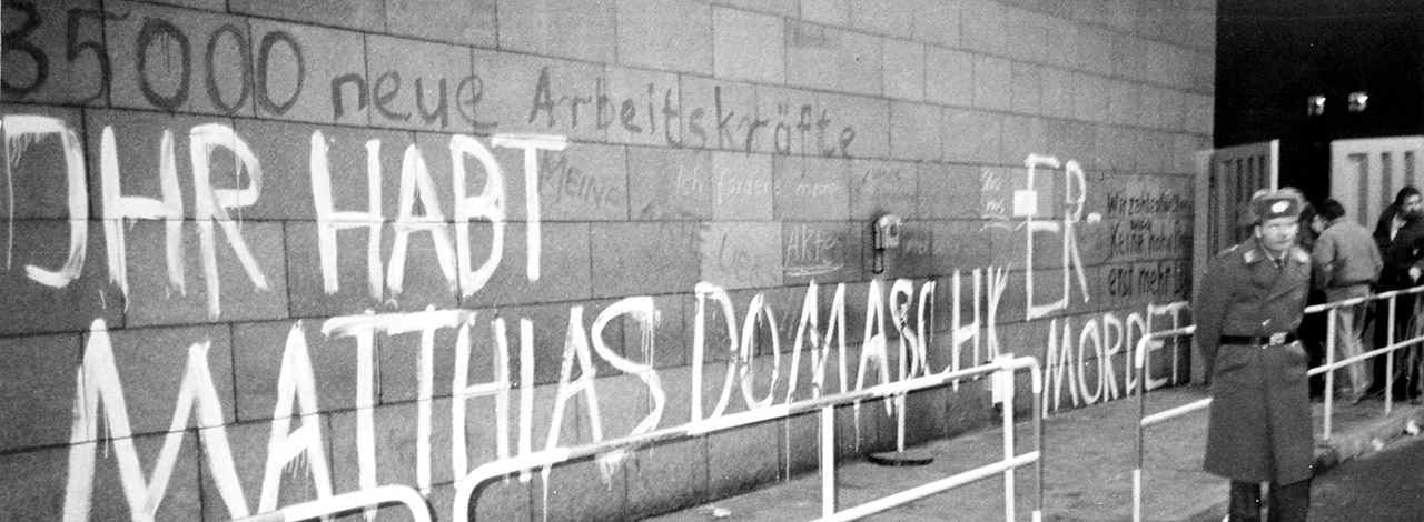 Hinter Absperrgitter Wand mit weißer Aufschrift Ihr habt Matthias Domaschk ermordert